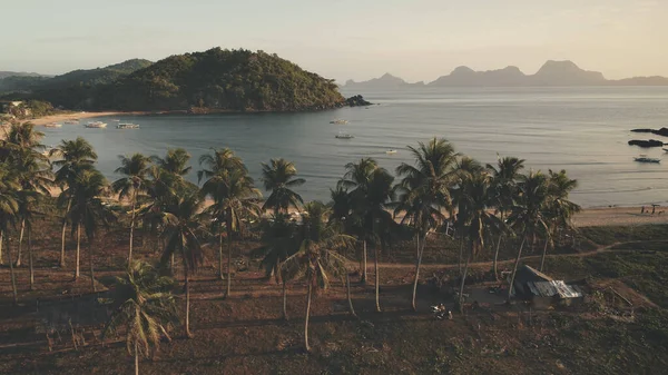 Tradiční loď na zelené trávě pobřeží antény. Turisté odpočívají na palmách. Písečná pláž v zálivu oceánu — Stock fotografie