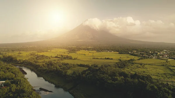 Tropisk sol skiner över floden vid vulkanens antenn. Åkrar, ängar på ingen natur landskap — Stockfoto