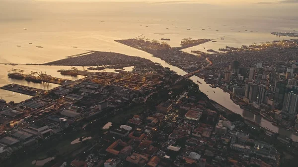 Sunset at ocean bay with city on river banks aerial. Illuminated cityscape with streets and roads — Stock Photo, Image