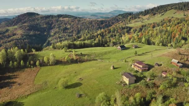 Vila no topo verde da montanha aérea. Ninguém paisagem da natureza. casas de campo com caminhos rurais — Vídeo de Stock