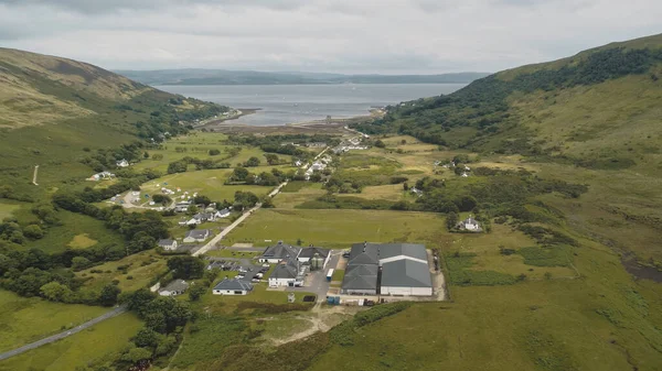 Шотландский ликеро-водочный завод в деревне. Дорога, дома. Природный ландшафт острова Арран — стоковое фото
