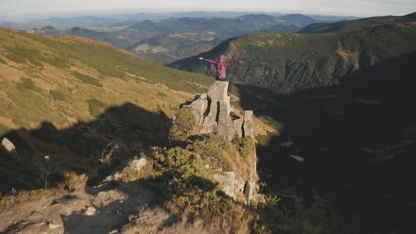 Kobieta podnosi ręce na górskich skałach. Jesienny krajobraz natury. Traveler dziewczyna siedzieć na kamieniu — Wideo stockowe