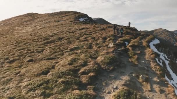 Caminhada turística até o topo da montanha aérea. Outono paisagem natural. Viajantes pessoas escalam na neve, grama — Vídeo de Stock