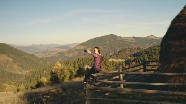 太陽の山で自撮りしている女性。農村の自然景観。丘の上のフェンスで — ストック動画