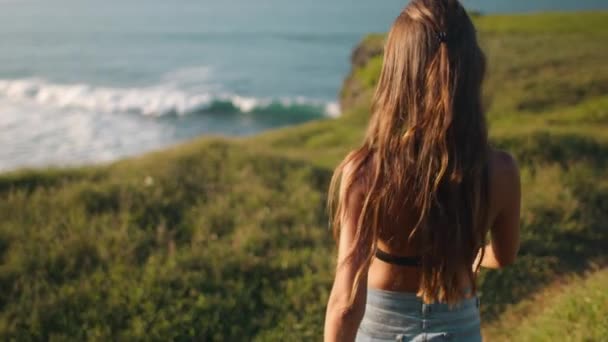 Bokeh Indonesia Wild Beach: kvinna vandring bred grön gräsbevuxen äng till klippa havsvik stranden. Havsvåg — Stockvideo