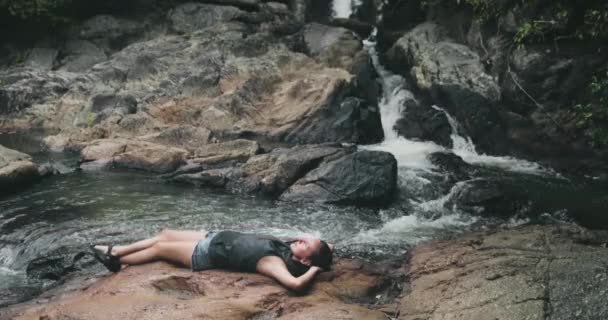 Tayland, Ulusal Park Şelalesi: kadın su düşüşünde büyük bir taşın üzerinde dinleniyor. Thai açık hava eğlencesi — Stok video