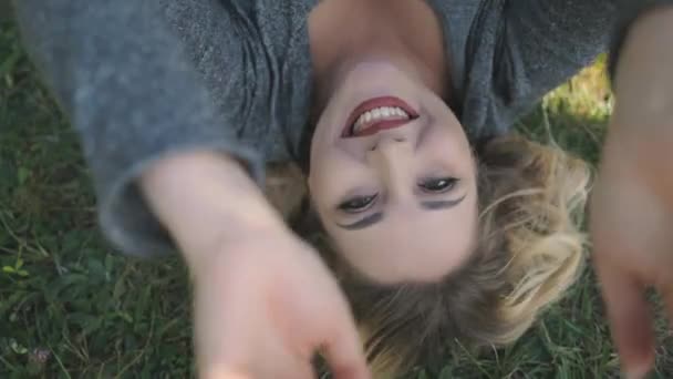 セクシーな女の子とサイズの笑顔を見るカメラのクローズアップ。ボディプラスモデルは公園で緑の芝生の谷に横たわっています — ストック動画