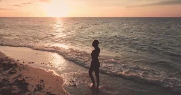 Молода жінка ходить на піщаному пляжі океану під час заходу сонця. Літній ландшафт природи. гарненька дівчина — стокове відео