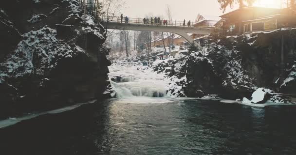 Zimní letovisko s turisty na mostě. Horský vodopád s peřejemi. Přírodní krajina — Stock video