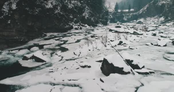 Blízká anténa tekoucí horské řeky. Zpomalte zimní krajinu přírody. Ledová voda na kamenech — Stock video