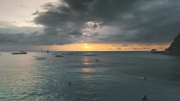 Puesta de sol aérea sobre la gente nadando, veleros en la bahía del mar. Velero a la luz del sol reflejo del océano — Vídeo de stock