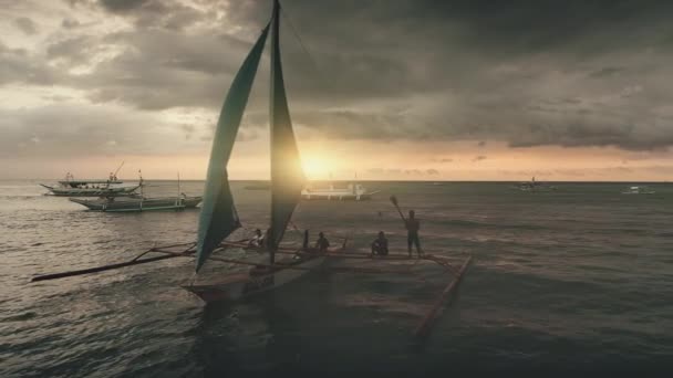 Filipinler, Boracay Adası, 2018.04.08: İnsanlı geleneksel teknenin gün batımı silueti — Stok video