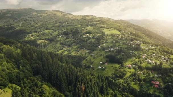 Luftaufnahme einer Bergstadt auf einem grünen Grashügel. Niemand Naturlandschaft. Sonne scheint über dem Frühlingswald — Stockvideo