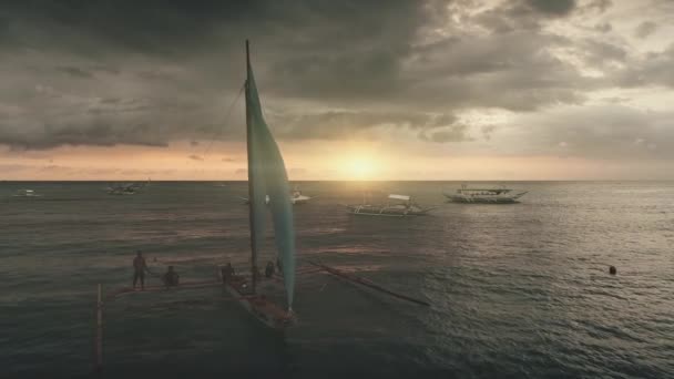 Filippinerna, Boracay Island, 2018.04.08 Passagerarsegelbåt vid solnedgången antenn. Segelbåt kryssning till sjöss — Stockvideo