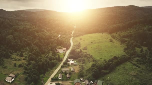 Sol sobre el verde pueblo de montaña aérea. Camino rural. Bosque de pinos. Paisaje de la naturaleza rural — Vídeos de Stock