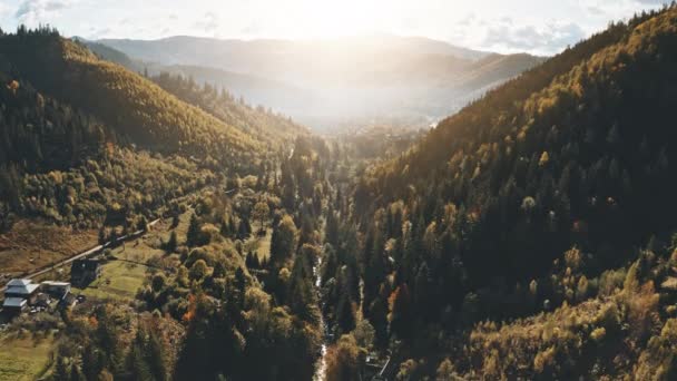 ดวงอาทิตย์ส่องแสงเหนือหมู่บ้านภูเขาที่ป่าฤดูใบไม้ร่วงทางอากาศ พื้นที่ธรรมชาติ คอทเทจที่ถนนคันทรี่ — วีดีโอสต็อก