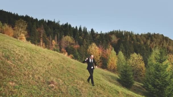 Forretningsmand fejre sejr udendørs bjerglandskab. Selvsikker ung mand i jakkesæt kører – Stock-video