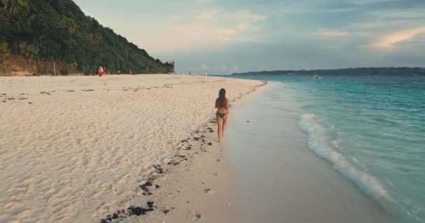 Frau läuft morgens am tropischen Strand. Rückansicht. Junge schöne Mädchen im Badeanzug joggen im Freien — Stockvideo