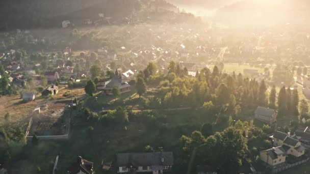 Europeisk bergsby i solnedgången. Flygfoto över grön kulle med kyrka på toppen, lantliga hus — Stockvideo