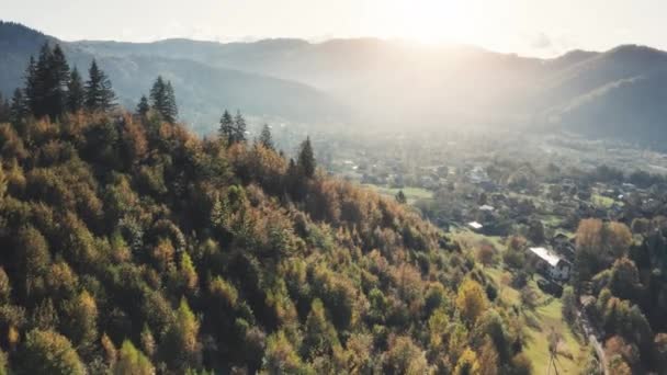 Letecký let nad vesnicí horských lesů. Západ slunce krajina scéna: borovice kopec, venkovské domy — Stock video