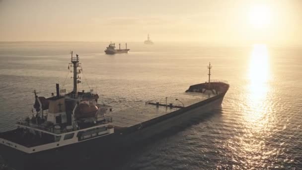 Navio de carga grande aéreo que navega sol pôr-do-sol laranja. Vôo baixo sobre embarcação vazia cruzando mar alto — Vídeo de Stock