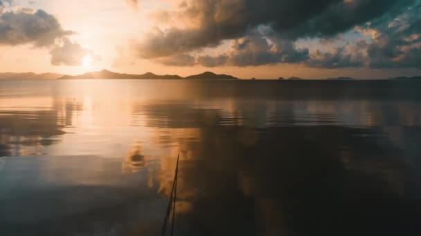 Solnedgång färgglada moln reflekteras i spegeln havet vatten. Orange och blå färger. Båt ankrad på land — Stockvideo