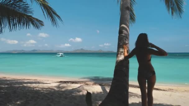 Agua turquesa de playa. La gente se relaja en la isla tropical. Mujer joven cerca de la palmera mirar el horizonte del mar — Vídeo de stock