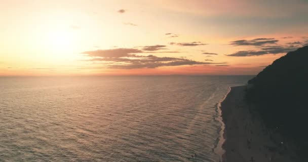 Luftburet strandlandskap. Ljus havssolnedgång längs kusten. Orange moln himmel återspeglas i havsvågor vatten — Stockvideo