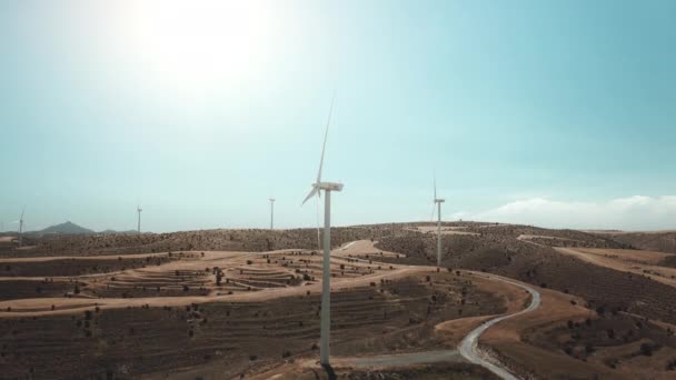 Windräder in der Luft, leere Wüstenstraße, gelber Hügel. Filmischer Drohnenblick auf große Windmühlenflügel — Stockvideo