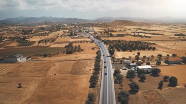 Coches conduce en el desierto de la carretera aérea. Campos amarillos, jardín y cordillera. Viaje de verano a Chipre — Vídeo de stock