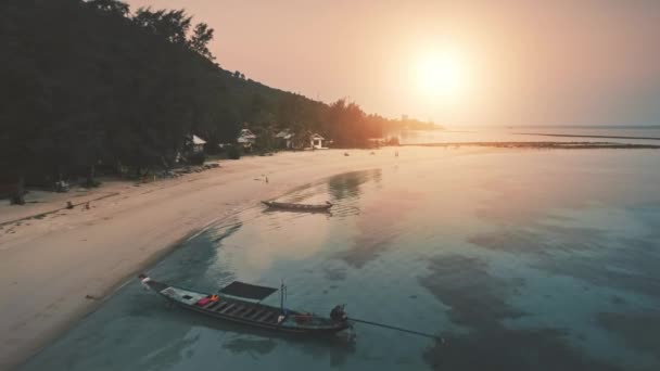 Voo lento sobre a praia com palmeiras, nascer do sol retroiluminado. Natureza paisagem colorida, casas na areia. — Vídeo de Stock