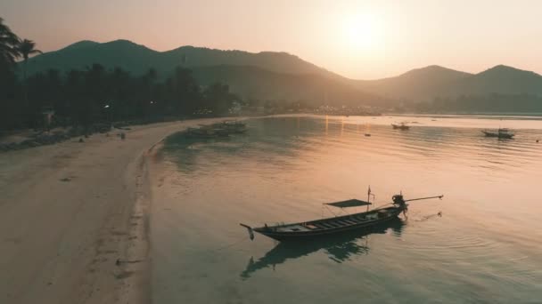 木々、黄金の時間と海の山の上に空中ビューの夕日。砂浜のカラフルな海岸近くの空のボート — ストック動画