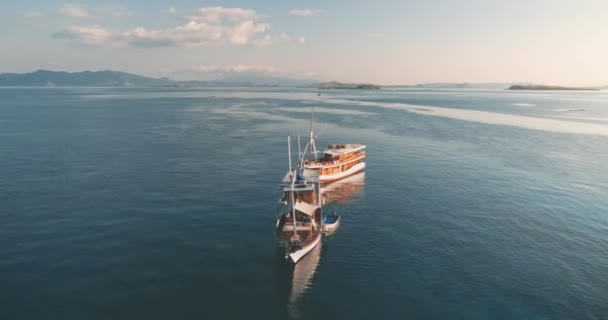 Panorama aéreo de dos yates de madera anclados cerca de islas tropicales de Indonesia. Tour en barco turístico. — Vídeo de stock