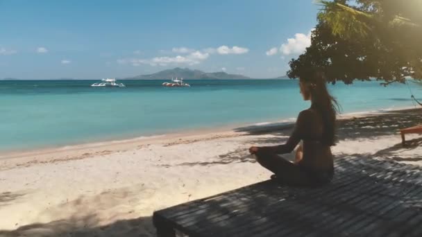 Luchtfoto jonge vrouw zit op het strand en kijkt naar boten in zee. Wit zand op eiland, blauw oceaanwater. — Stockvideo