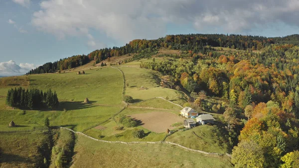 Pueblo de montaña en la parte superior aérea. Otoño nadie naturaleza paisaje. Montaje verde con cabaña. Vía rural —  Fotos de Stock