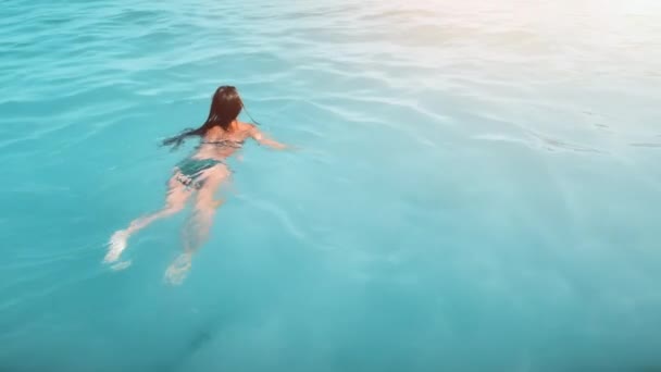 Εναέρια λεπτή γυναίκα με μαγιό κολυμπά στη γαλάζια θάλασσα, με θέα από πίσω. Πρωινή ανάπαυση σε καθαρό ζεστό νερό — Αρχείο Βίντεο