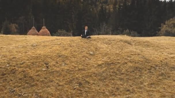 Homem medita na montanha na floresta de fundo, vista aérea. Outono grama seca, árvores verdes amarelas. — Vídeo de Stock
