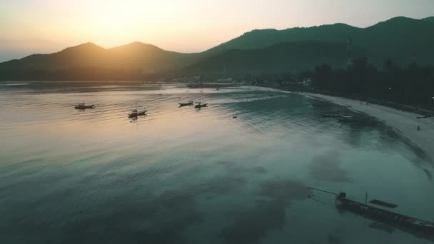 Sole serale splende barche in mare dietro le montagne, aerea. Drone cinematografico che sorvola l'oceano calmo. — Video Stock