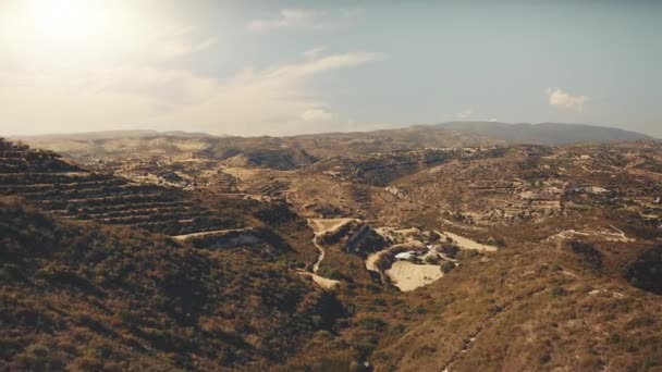 Chaîne de montagnes rocheuses jaune aérienne contre un ciel bleu ensoleillé. Herbe sèche, buissons verts dans les collines. — Video