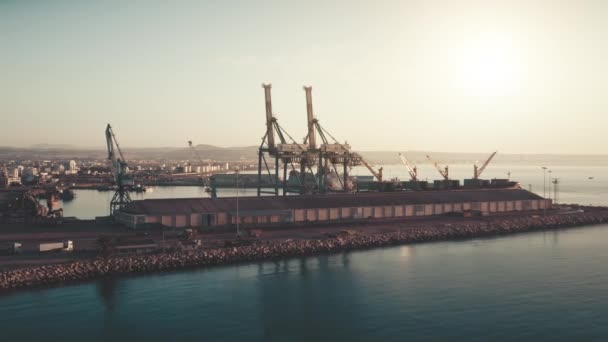 Vista aérea, sol brilha no mar e guindastes no porto. Berço para carregar e descarregar navios. Céu azul — Vídeo de Stock