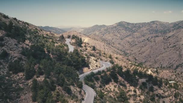 Vista aérea sinuosa auto-estrada nas montanhas. Colinas de areia rochosa e árvores. Voo de drone cinematográfico — Vídeo de Stock