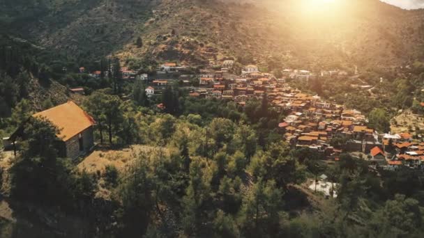 Aerial view, sunlight over village and trees in rocky mountains and gorges. Drone flight over houses — Stock Video