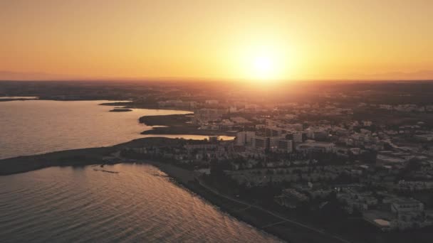 Aerial belo nascer do sol laranja sobre a cidade por mar. Reflexões de ondulações, em águas limpas do oceano escuro. — Vídeo de Stock