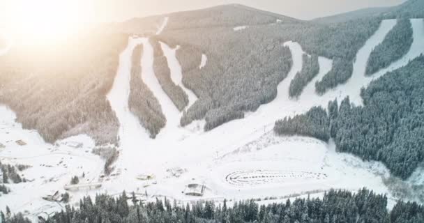 Ski mountain resort légi kilátás. Bukovel, Ukrajna, Kárpátok. Havas lejtő, fenyőerdő, naplemente — Stock videók