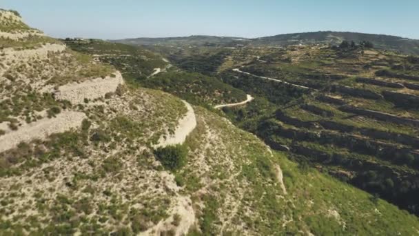 Letecký pohled na zelenou skalnatou poušť divoké horské oblasti s klikatou cestou na Kypru — Stock video