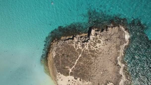 Arriba aérea hacia abajo isla rocosa en el mar turquesa. Isla aislada y agua azul del océano — Vídeo de stock