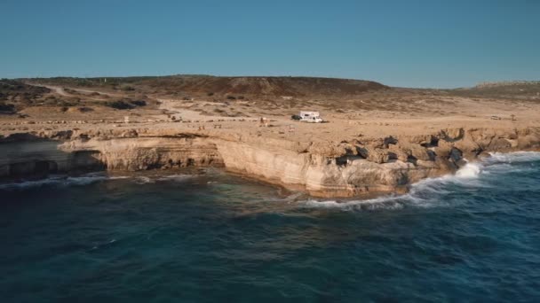 Rotsgrotten aan zee strand baai op zomereiland. Zonsondergang op rotsachtige kust oceaan — Stockvideo