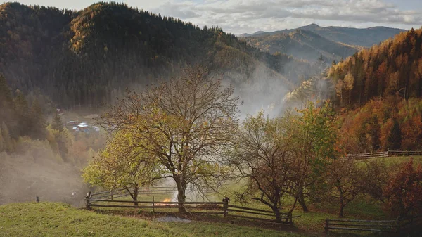 Aérea de nubes de neblina sobre el pueblo de montaña de otoño. Campos, bosque en cabañas en niebla ahumada —  Fotos de Stock