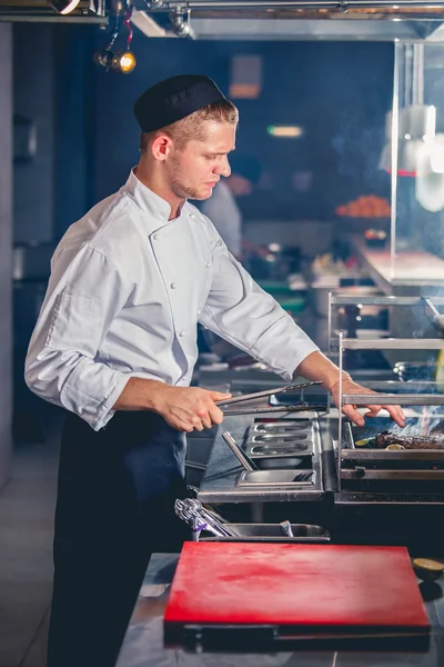 Männlicher Koch bereitet Essen auf dem Grill zu — Stockfoto