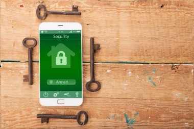 Ahşap masada akıllı ev uygulaması olan akıllı telefon.